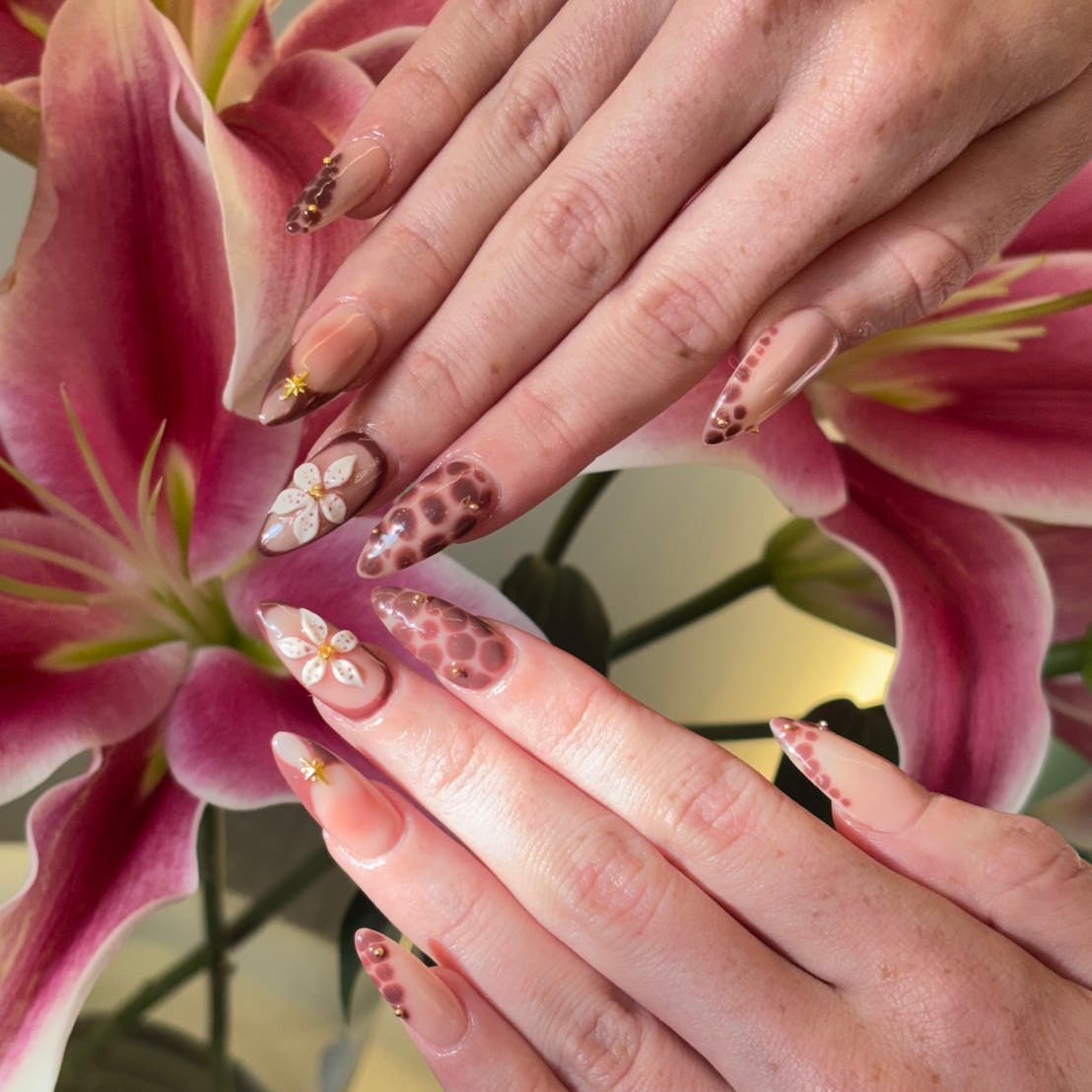 Pink floral nail art photographed among lilies