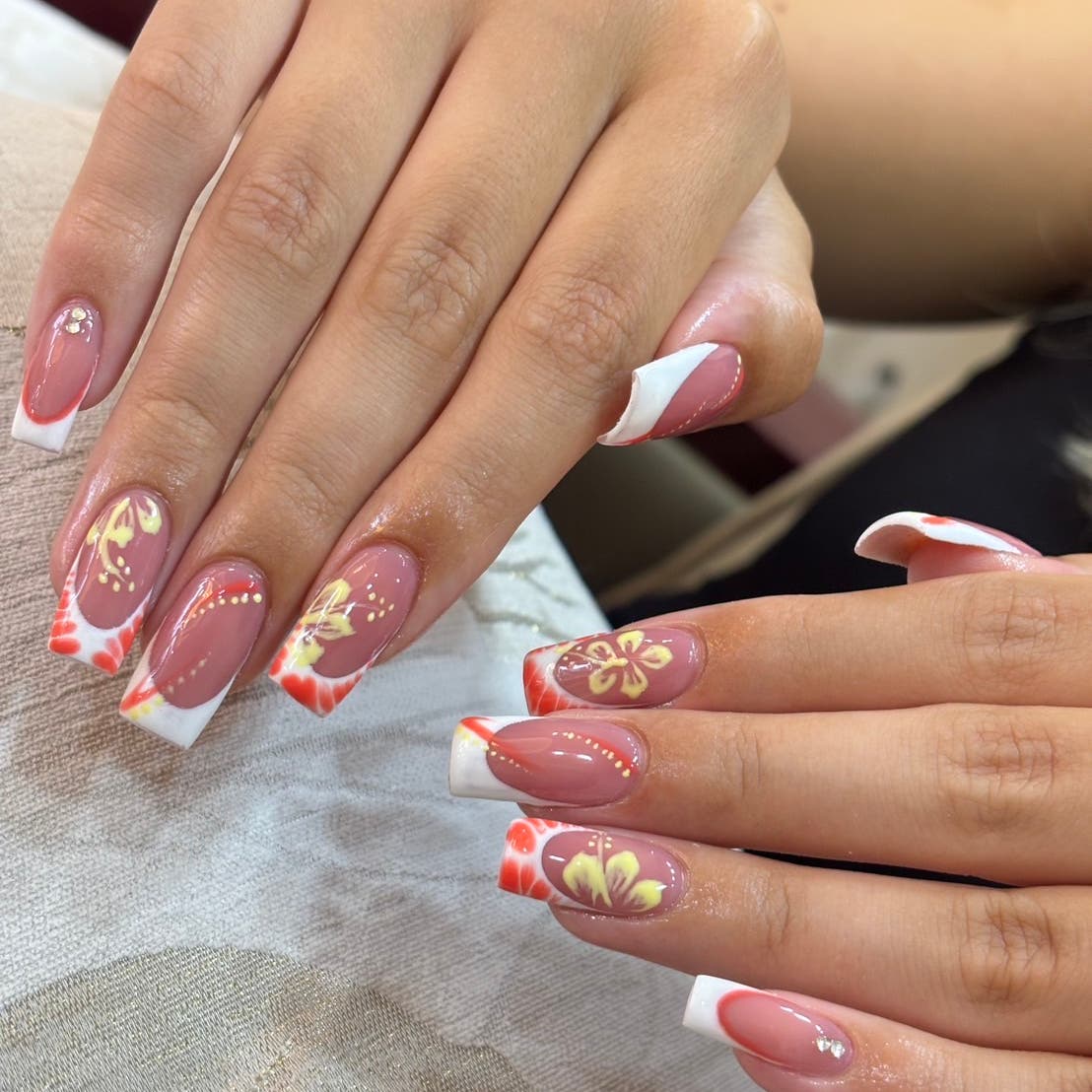 Pink gel nails with floral accents and French tips